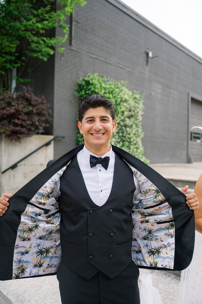 Groom revealing the custom tropical-print lining inside his black ABR tuxedo