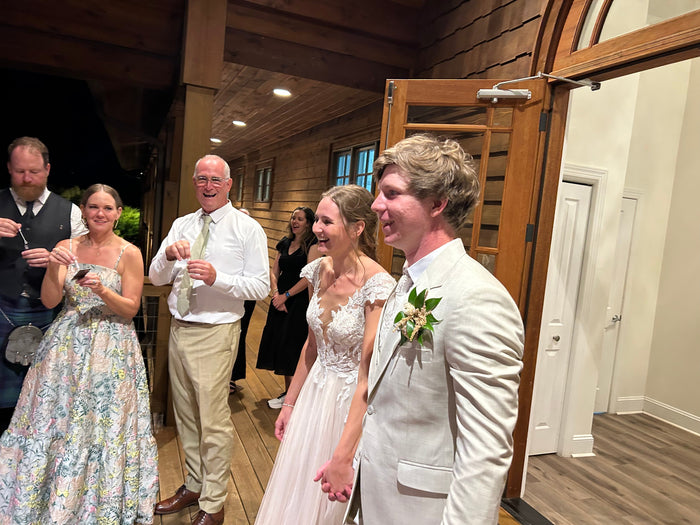 Bride and groom in a light sand suit entering their reception hand in hand